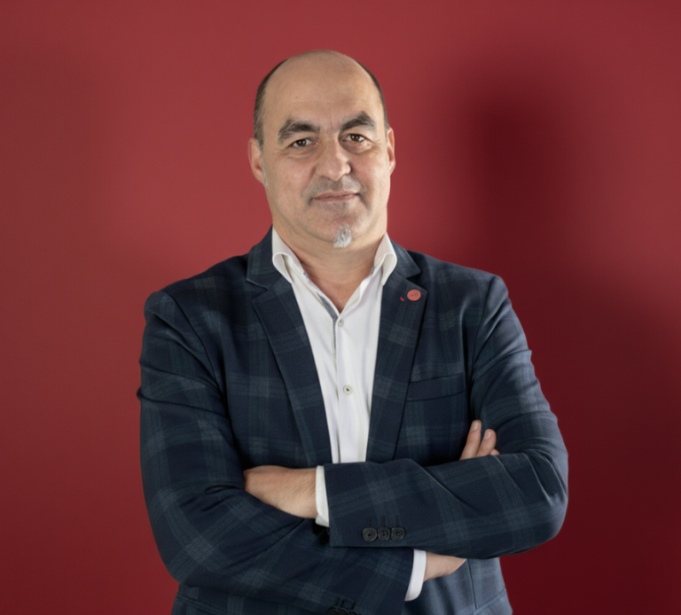 David Gonzalo tu gestor en barcelona y Santa Coloma de Garmanet Hombre con chaqueta de cuadros, brazos cruzados y fondo rojo. David Gonzalo tu gestor seag